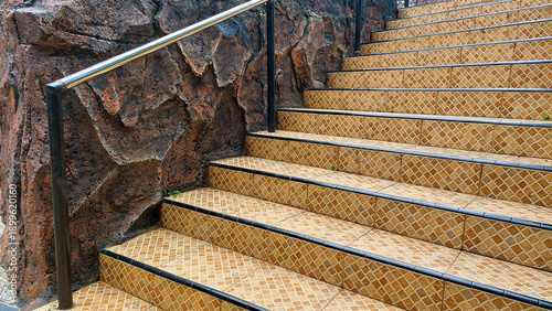 Outdoor Tiled Staircase with Metal Handrail and Rock Wall