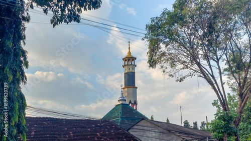 Old traditional Mosque Minaret and Roof Under a Cloudy Sky in a Residential Area