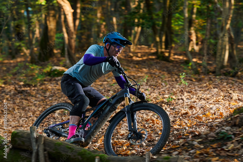 Fototapeta premium Intense Mountain Biker Navigates Leafy Forest Trail With Focus, Gear, and Adrenaline