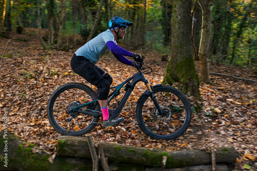 Fototapeta premium Autumn Forest Mountain Biker Navigates Rugged Trail With Focus And Speed