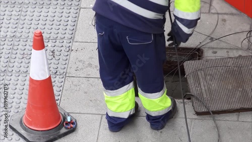 electrician worker install traffic light or optical fiber cables for internet and telephone underground lines in city street , horizontal full hd video footage 