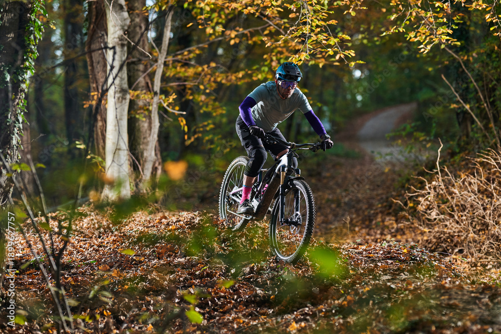 Naklejka premium Autumn Forest Mountain Bike Rider On Dusty Trail With Dappled Sunlight And Gear Adventure