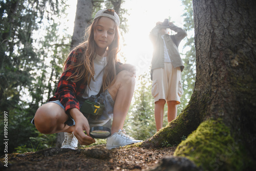 Young explorers investigating forest soil with magnifying glass