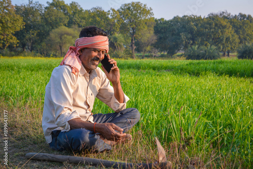 Indian farmer talking on mobile phone in green field. Digital connectivity in rural farming life