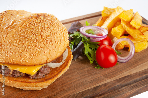 Hamburger with potatoes and vegetables on a wooden board