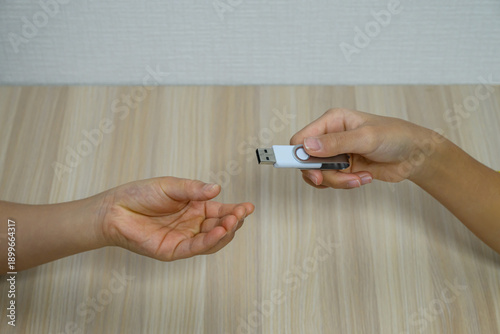 Photography Close up of a person passing a USB flash drive to another person