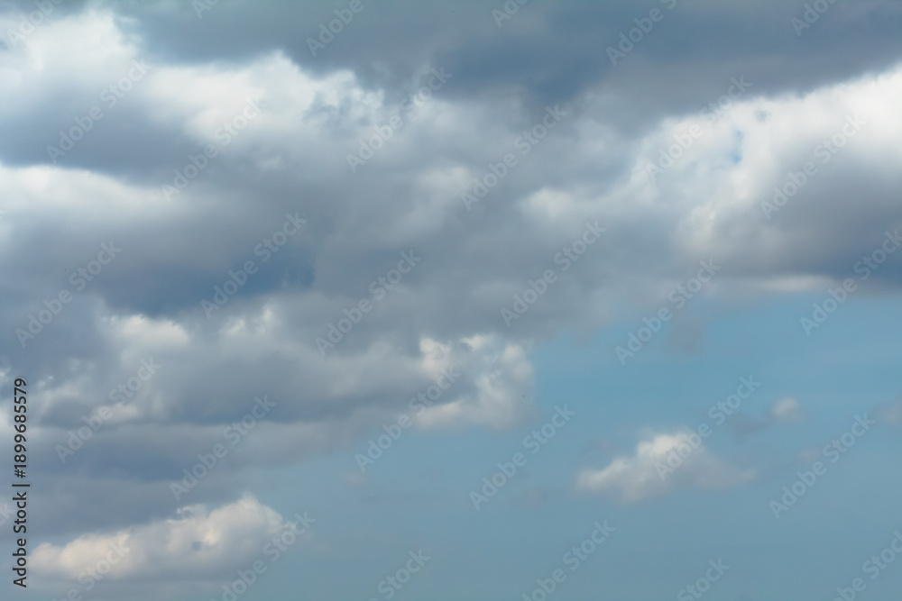 Fototapeta premium The sky is cloudy and the sun is not visible. The clouds are white and grey. The sky is blue and the clouds are scattered.