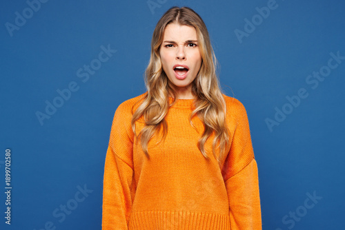 Obraz na płótnie Young sad displeased dissatisfied outraged angry mad Caucasian woman she wearing yellow sweater casual clothes looking camera isolated on plain blue wall background studio portrait