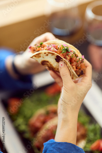 Close-Up Diner Moment: Hand Holding Fresh Tasty Taco With Salsa In Busy Dining Scene
