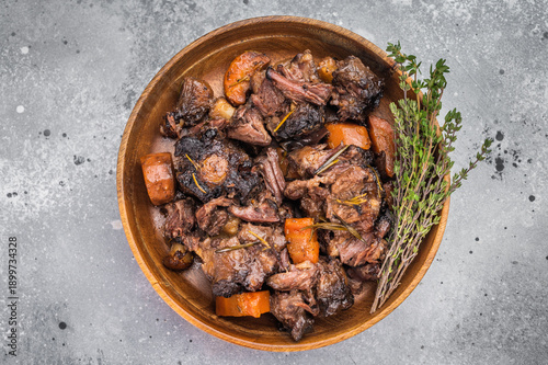 Valokuva Braised veal oxtail stew with carrots and herbs served in wooden bowl, tender sl