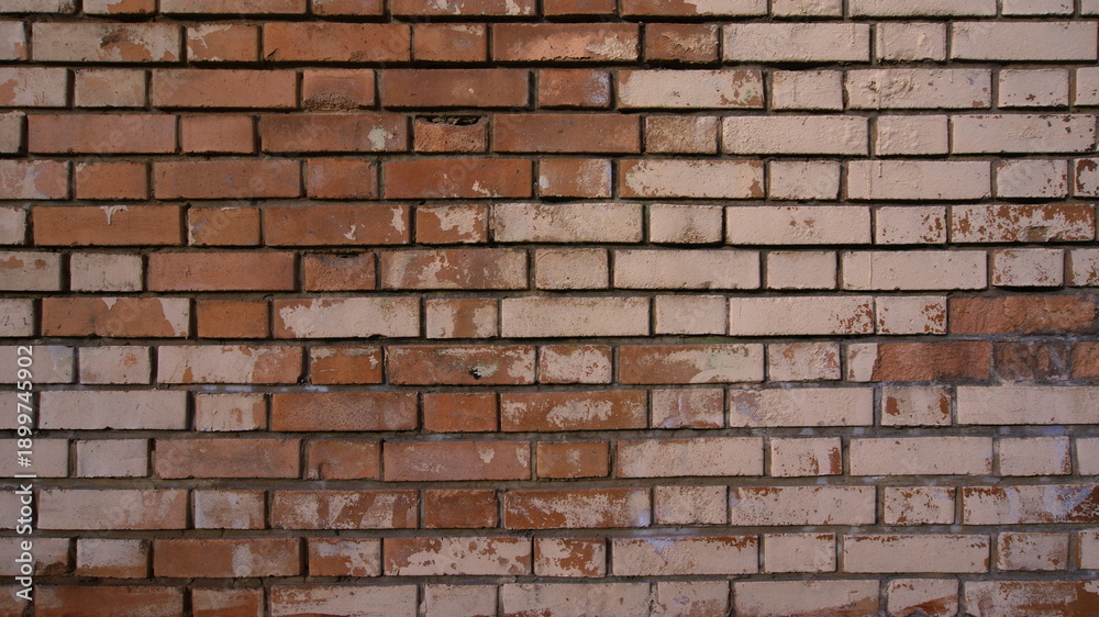Obraz premium An old worn brick wall with bricks in different shades of red and beige