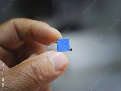 Photos The image shows the trimmer potentiometer being clamped between the fingers of a technician