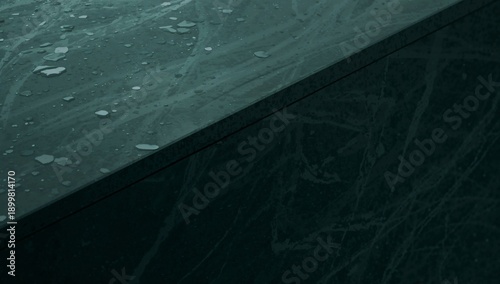 Water Droplets Rest on a Smooth Dark Stone Surface in a Quiet Indoor Space