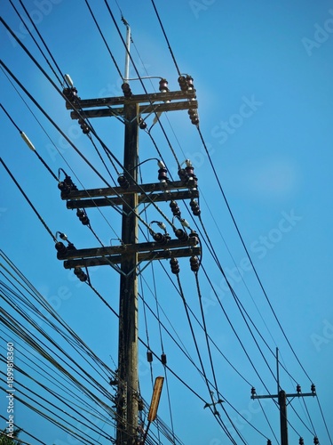 Low angle view of high voltage overhead power line automatic splice sleeve connector on concrete pole distribution grid against blue sky.