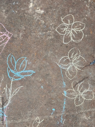Top view of simple flower drawings made with colorful sidewalk chalk on a rough concrete surface. Childlike chalk art with pastel lines and hand-drawn shapes, outdoor creativity.