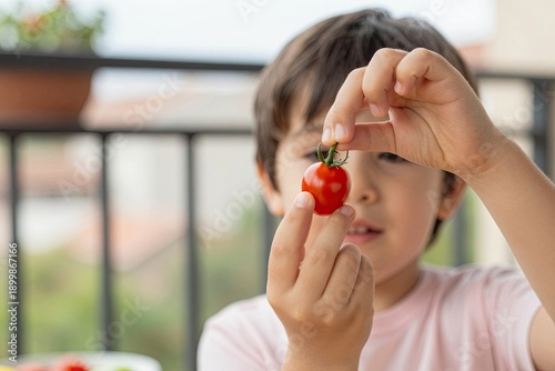 A child holds a small, bright red tomato
