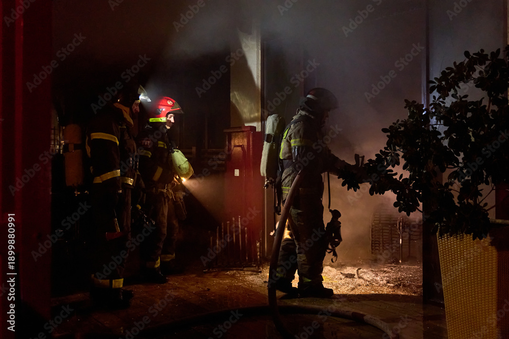 Obraz premium fire brigade extinguishes a burning building at night