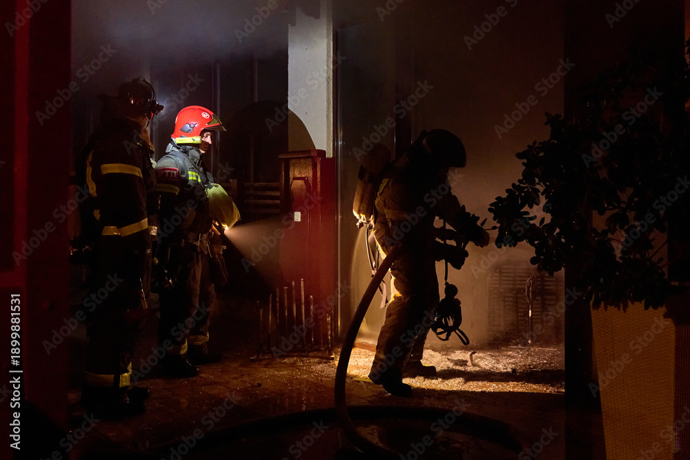 Fototapeta premium fire brigade extinguishes a burning building at night