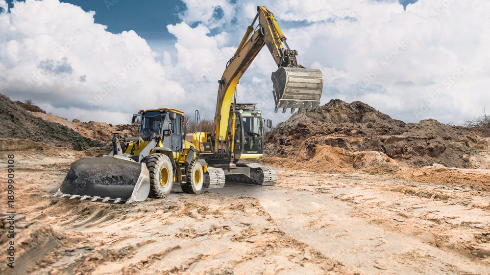 Obraz premium A loader and a crawler excavator work at a construction site. In the background, earthen embankments rise under a partly cloudy sky