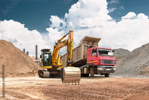 Foto An excavator moves sand from a mound into a truck at a busy construction site