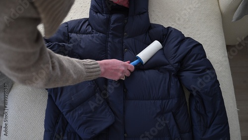 Foto Lint roller cleaning winter jacket removing pet hair and dust