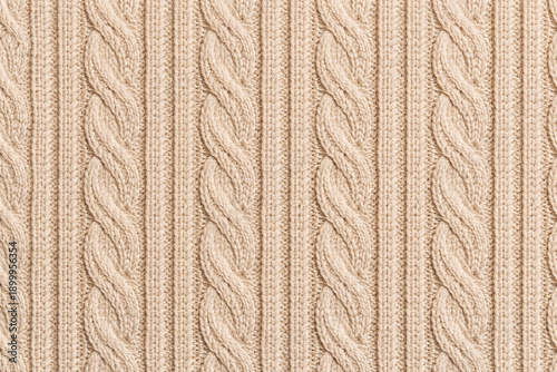 Close-up of beige cable knit fabric with classic braided pattern. Seamless knitted texture background suitable for cozy winter fashion, neutral textile design, seasonal decor