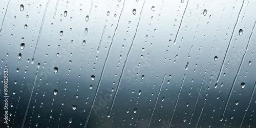 Close-up view of raindrops and streaks flowing down a window pane during a rainy day