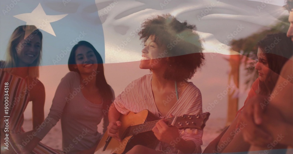 Fototapeta premium Playing guitarist strumming on sand at beach sunset, flag overlay, palm, wearing summer clothes