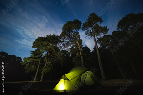 Illuminated tent in forest at night