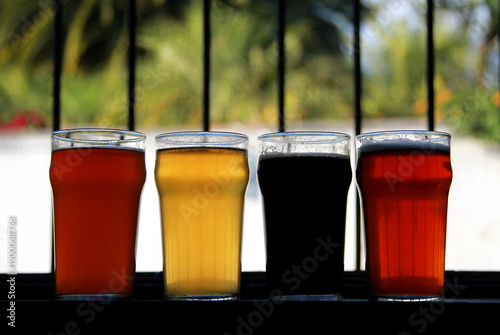 Valokuva Four glasses of craft beer with different colors standing in a row against a bright window