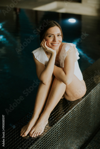 Woman sitting by pool smili...