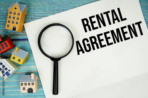фотографія Notepad with Rental Agreement with magnifying glass and house model on wooden
