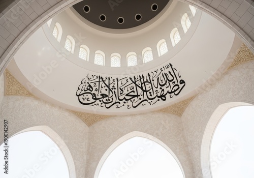 Interior view of a mosque with arabic calligraphy on the ceiling