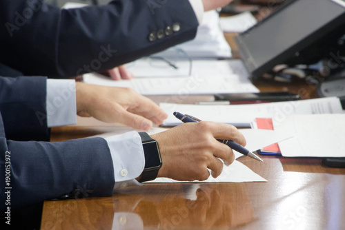 Male hand with a smartwatch ready to write notes during a negotiation. Concept of a politician, lawyer, or executive working with documents at a desk. Photo