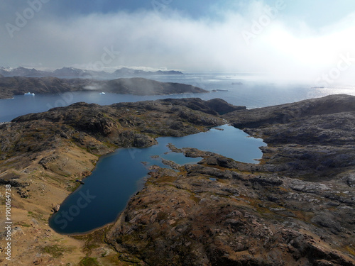 View of the waterfront infrastructure in Tasiilaq, Greenland. The clip shows the port area with shipping containers, fishing boats, and local housing, highlighting life in a remote Arctic community 