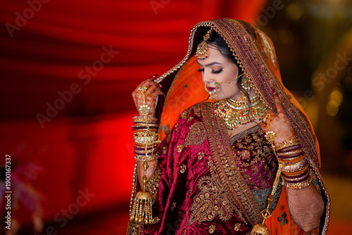 Foto Indian wedding bride wearing embroidered lehenga, heavy gold jewelry, veil, and mehndi hands, representing luxury bridal fashion, traditional ceremony, and premium wedding aesthetics