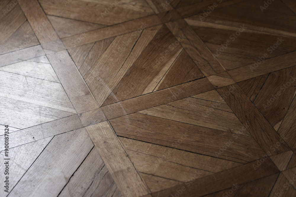 Obraz premium A warm wooden parquet floor featuring a geometric pattern of triangles and planks