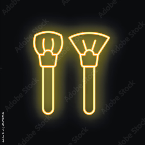 Yellow neon sign representing two makeup brushes glowing on a black background