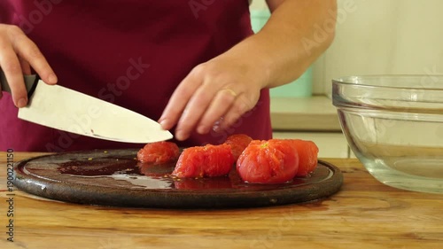 Woman cooking sauce with fresh tomato at the kitchen