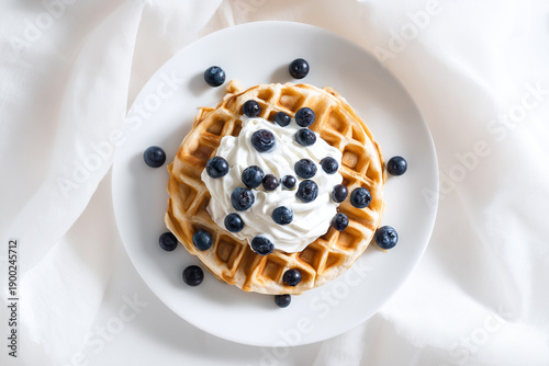 Golden waffle topped with whipped cream and fresh blueberries