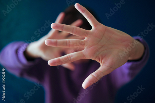 Bild auf Leinwand Woman wearing purple sweatshirt with hands up covering face from camera