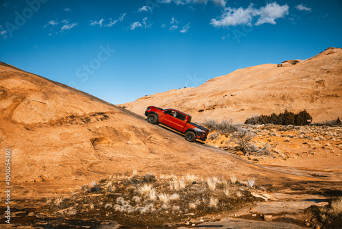 Off road pickup truck climbing steep sandstone slope in desert landscape at Sand Flats Recreation Area