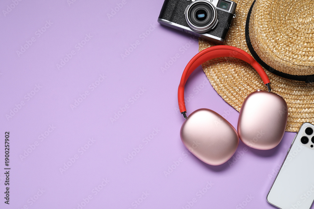 Obraz premium Headphones, smartphone, vintage camera and straw hat on violet background, flat lay. Space for text