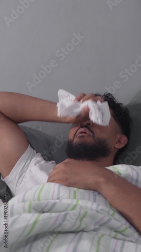 Sick man with fever suffering from illness lying in bed