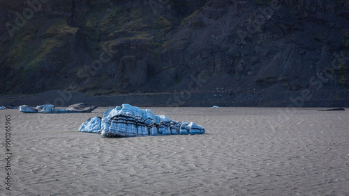 Solheimajokull glacier lagoon blue iceberg with black volcanic ash bands, Iceland
