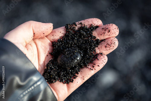 Reynisfjara Black Sand Beach volcanic granules and pebble held in a hand, Iceland