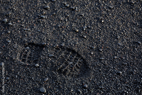Reynisfjara Black Sand Beach boot footprint on wet volcanic sand and pebbles, Iceland