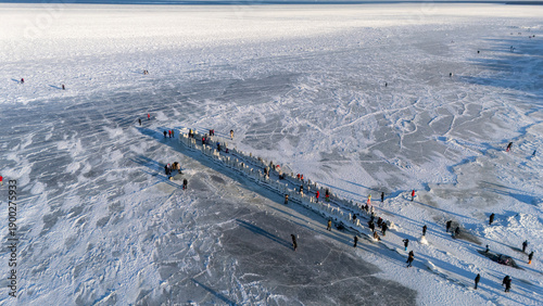 Frozen Baltic Sea At Beach With Ice Covered Old Wooden Pier And People Walking On The Ice Enjoying A Sunny Winter Day Scenic Latvia 4K Footage For Travel Nature Seasonal Projects