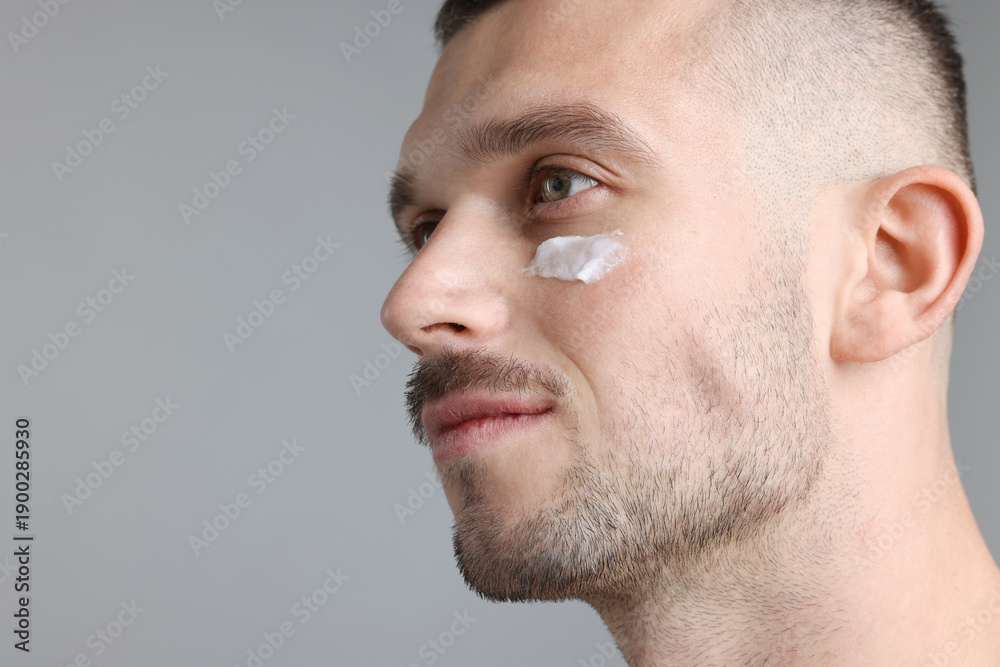 Obraz premium Handsome man with cream on his face against light grey background. Space for text