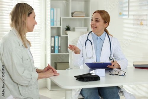 Photography Smiling woman having appointment with cardiologist at table in clinic